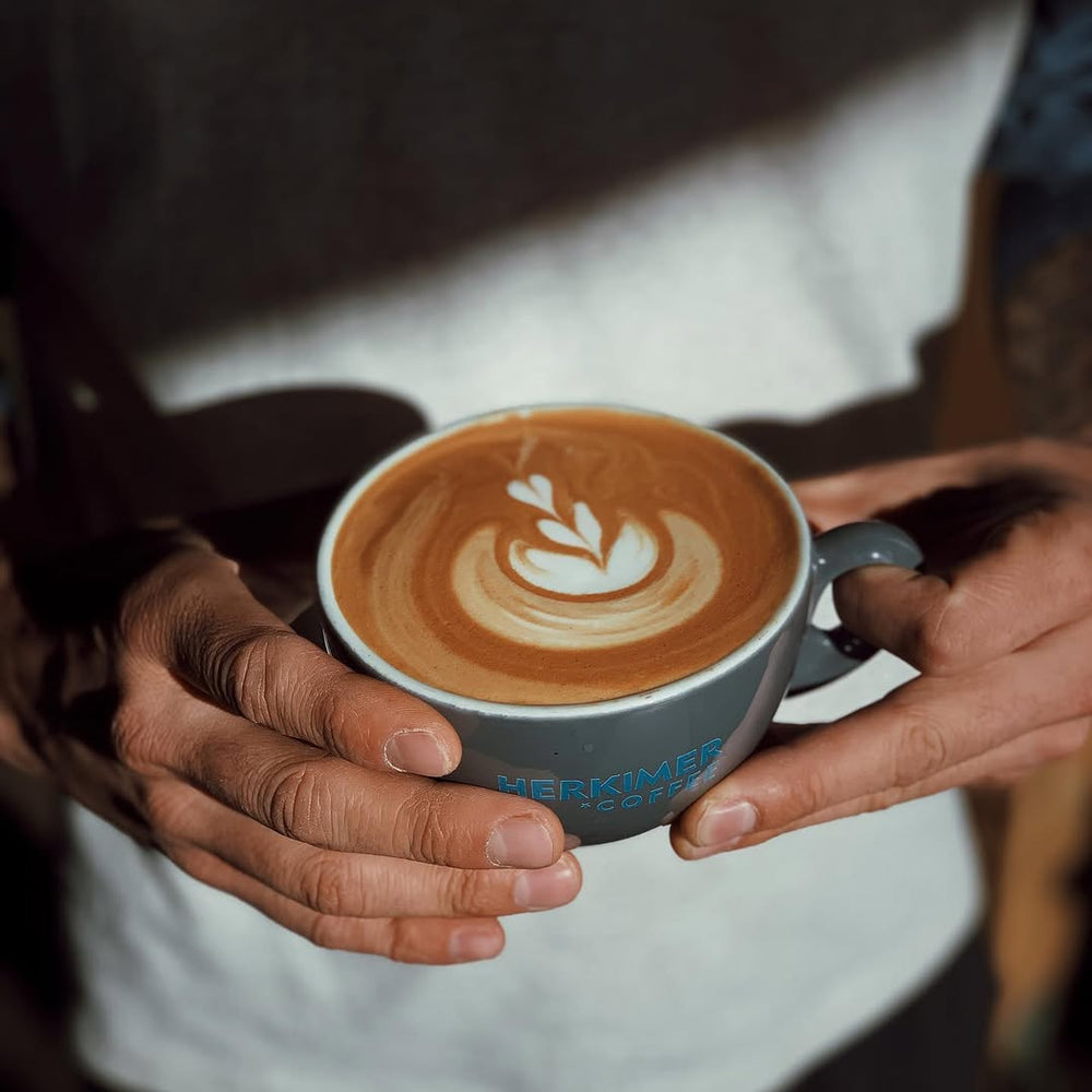 Hands holding a cup of coffee with latte art